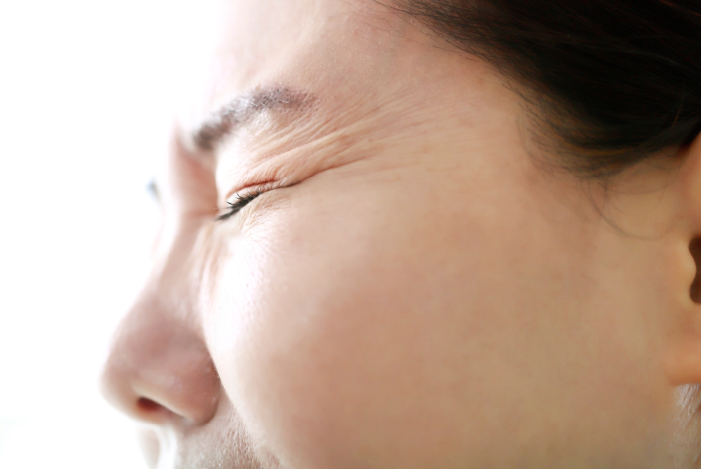 갑자기 눈앞이번쩍하는 광시증 증상 때문에 눈을 찡그리며 불편해하는 사람의 얼굴